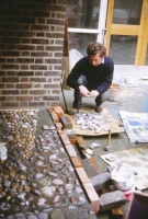 Kennedy lays stones into the wet cement render. We organise the backing stones into drifts and layers to give a consistent but lively background to the different figures. - click to enlarge Kennedy lays stones into the wet cement render. We organise the backing stones into drifts and layers to give a consistent but lively background to the different figures.