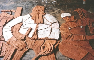 The figures of two steel workers are seen lying on the studio floor. One wears goggles and the other holds a heavy chain. The clay has been biscuit fired so appears terracotta, and awaits the application of glazes and further firing. - click to enlarge The figures of two steel workers are seen lying on the studio floor. One wears goggles and the other holds a heavy chain. The clay has been biscuit fired so appears terracotta, and awaits the application of glazes and further firing.