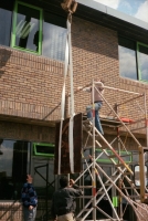 Lifting the Siskin House watermark panel into position to be fixed on the wall.